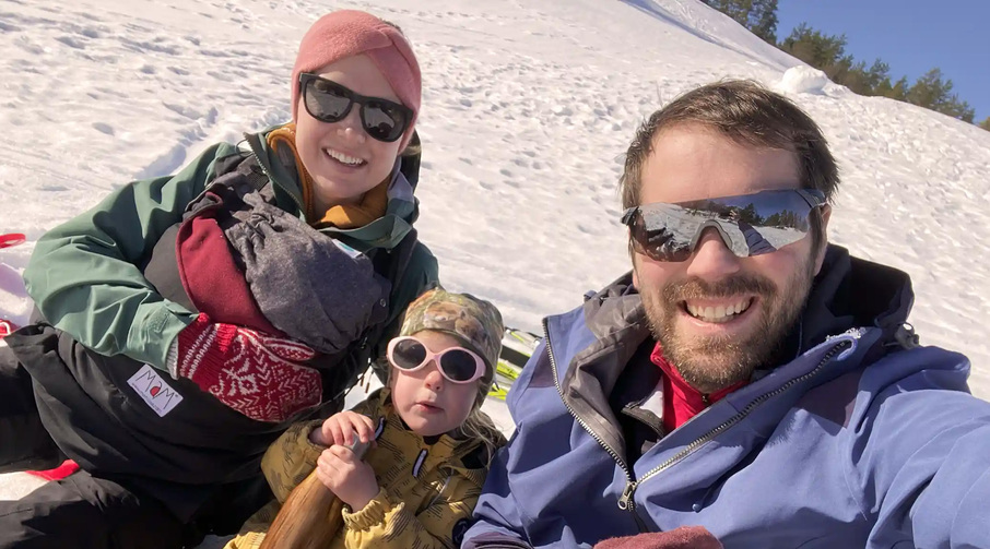 To voksne og to barn ute i snøen med solbriller.
