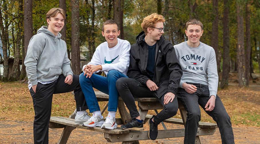 Fire kompiser på 15 år sitter på en benk.